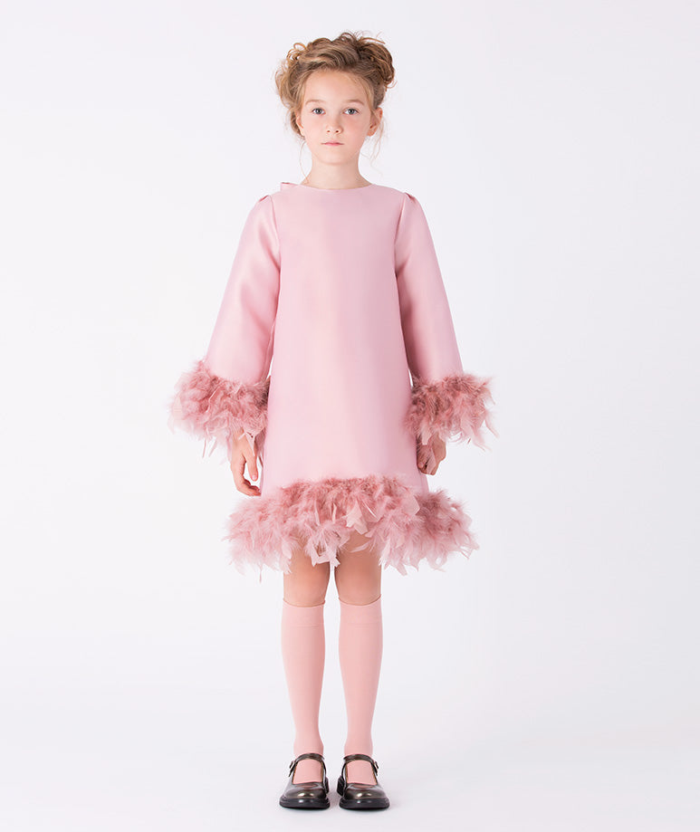 sleek pink dress with playful feather trims at the hem and cuffs