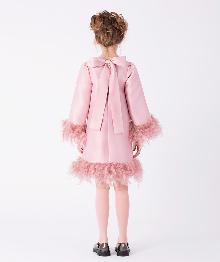 sleek pink dress with feather trims at the hem and cuffs, and a bow on the back