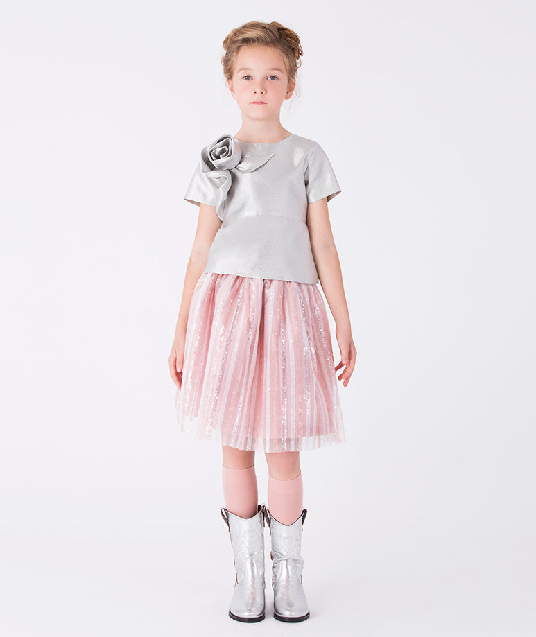 A structured silver blouse with short sleeves and a 3D rose detail, paired with a playful pink striped glittery skirt