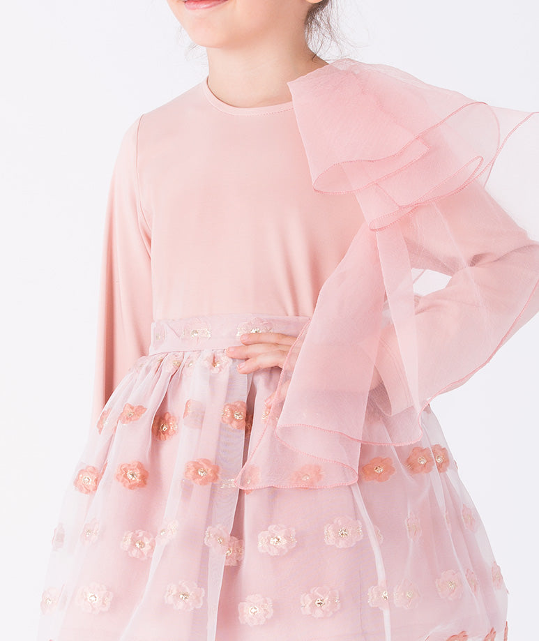 a soft pink top with oversized tulle ruffle and a textured floral skirt
