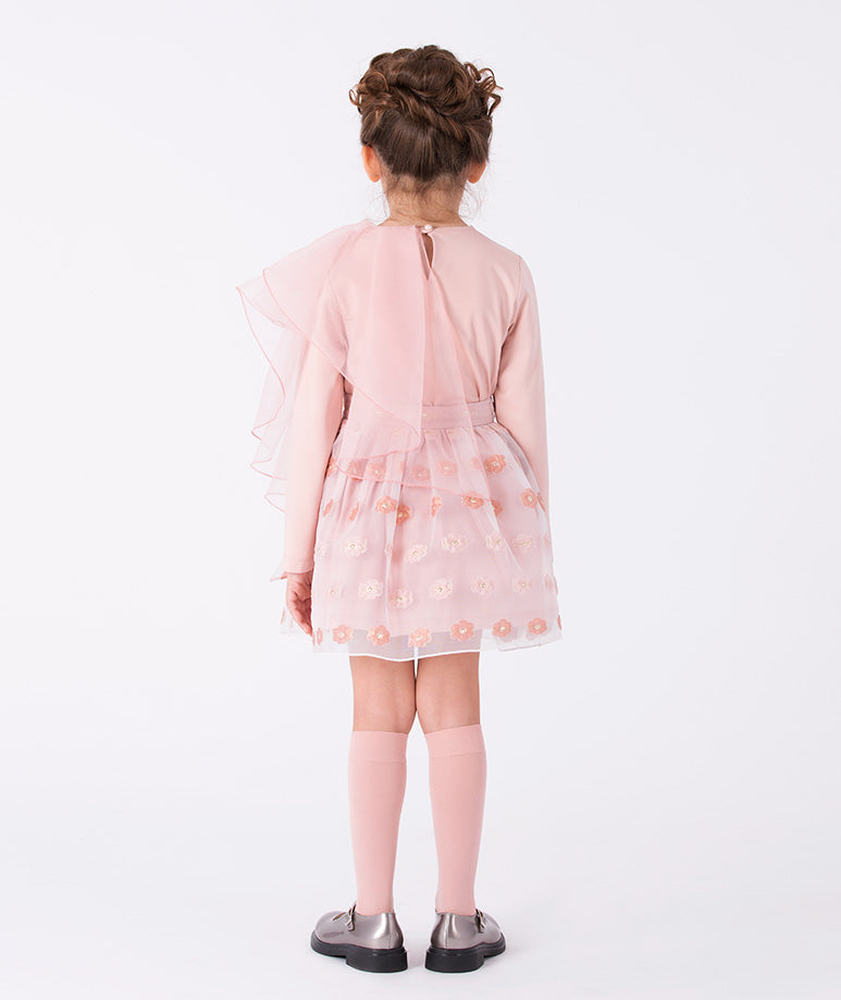 a soft pink top and a textured floral skirt