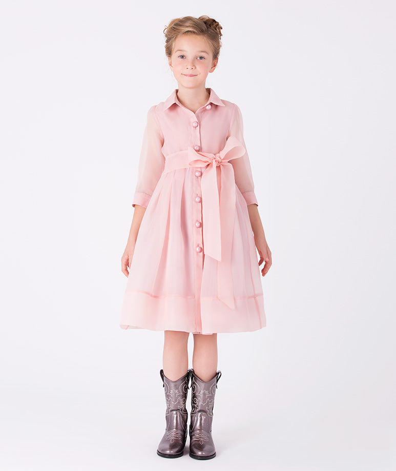 A polished shirt dress in a soft peach-pink hue, elevated with a sheer overlay skirt and tie-neck detail