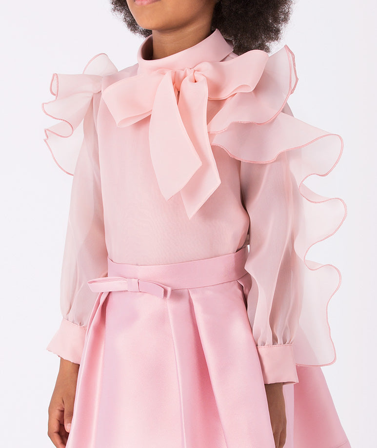a voluminous bow blouse with dramatic ruffle sleeves and a classic pleated skirt