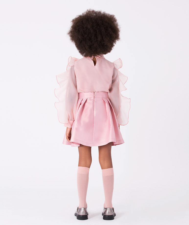 a voluminous bow blouse and a classic pleated skirt