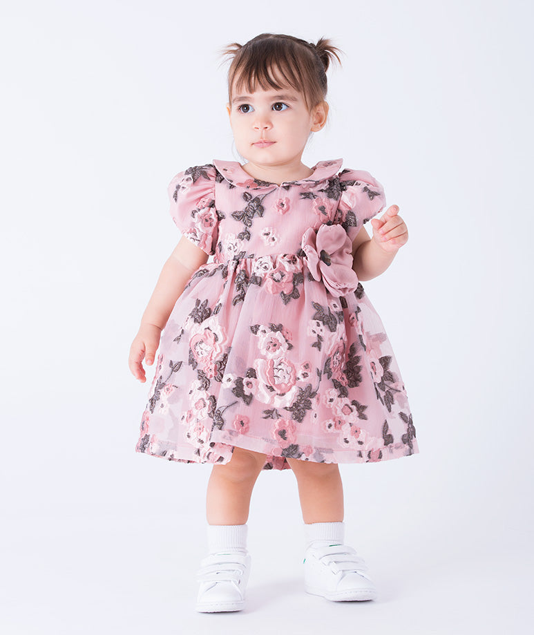 A charming baby dress in soft pink with allover floral prints, puff sleeves and a 3D flower on the waist