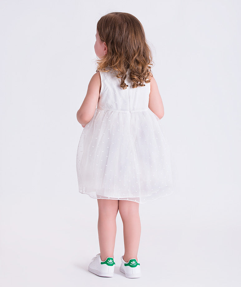 Back view of a swiss dot baby girl dress with lightweight fabric and gentle volume, designed for babies aged 12–36 months.