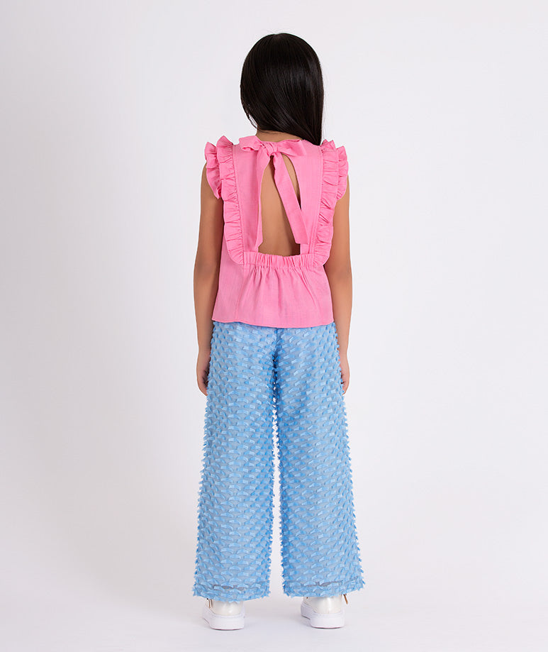 pink blouse with an open back and textured blue pants