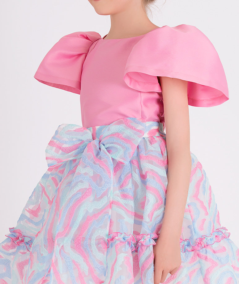 pink blouse with balloon sleeves and pink and blue printed skirt with a bow on the waist 