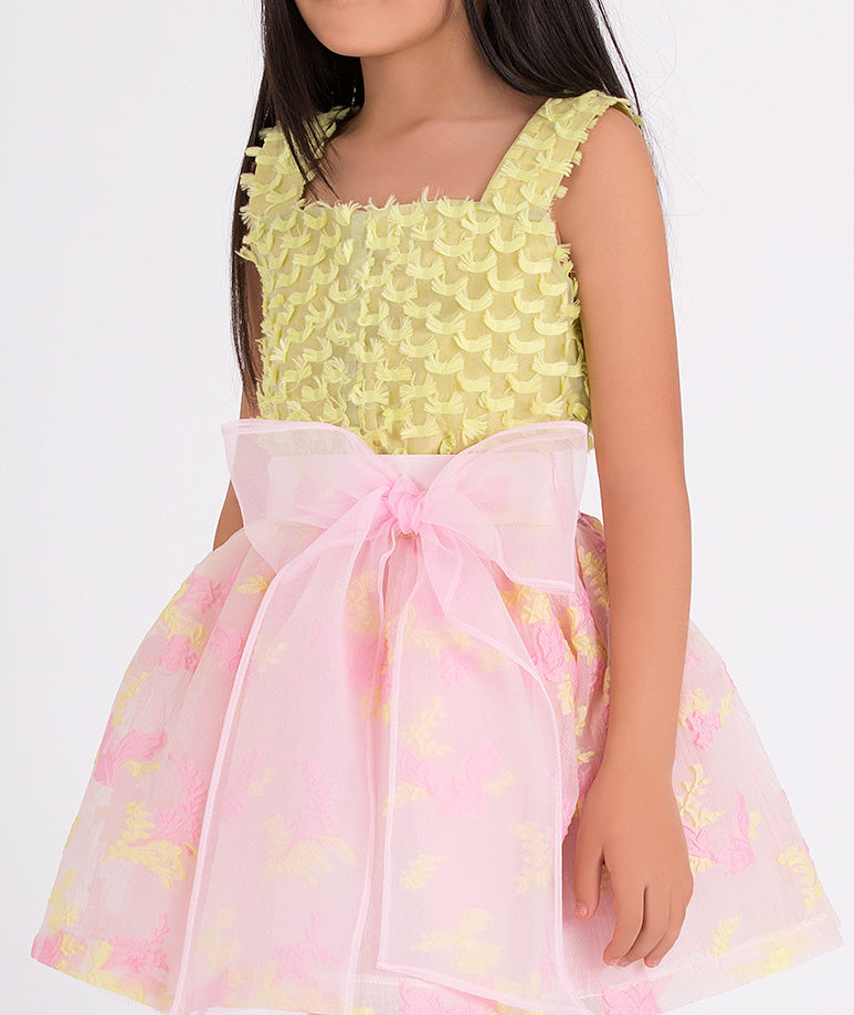 yellow textured blouse and pink floral skirt with a big bow on the waist