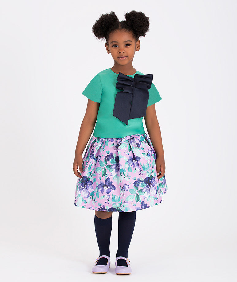 a stylish floral skirt and green top with a large navy bow accent