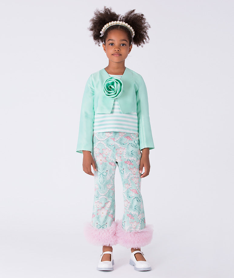 Young girl wearing a mint green outfit with floral pants on a white background