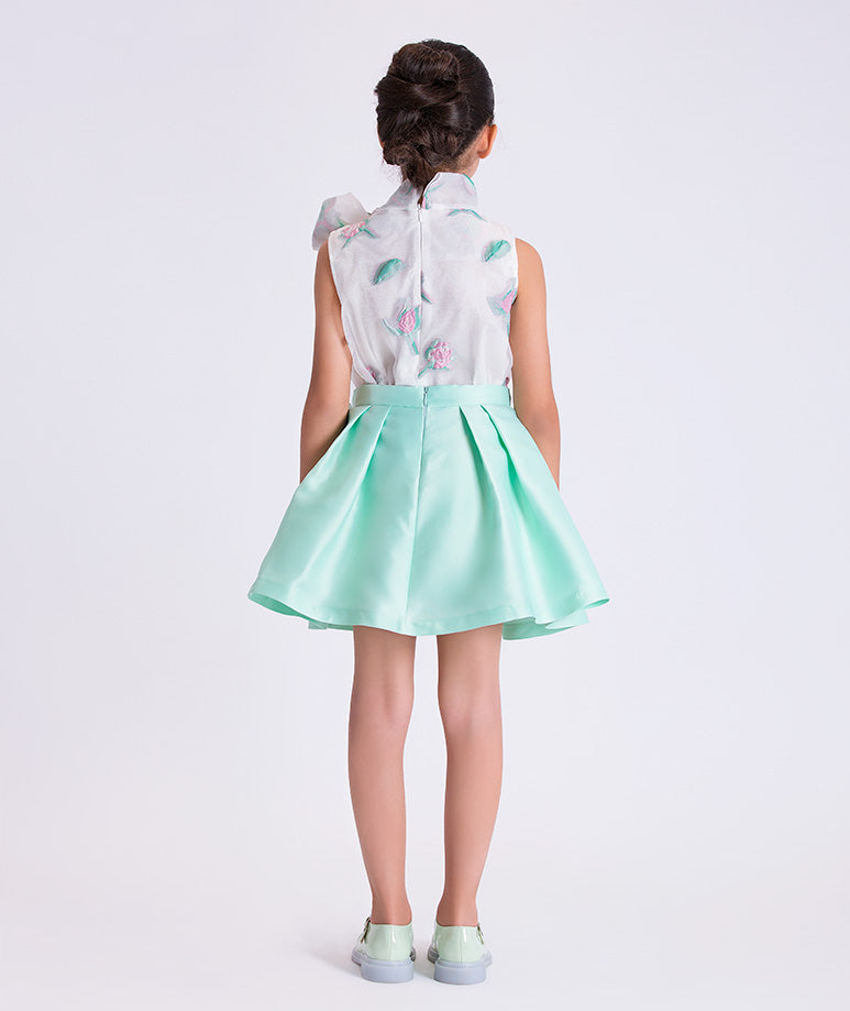 Person wearing a floral blouse and light green skirt on a white background