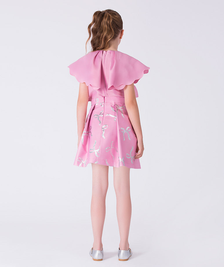 Girl wearing a pink dress with ruffled sleeves on a white background