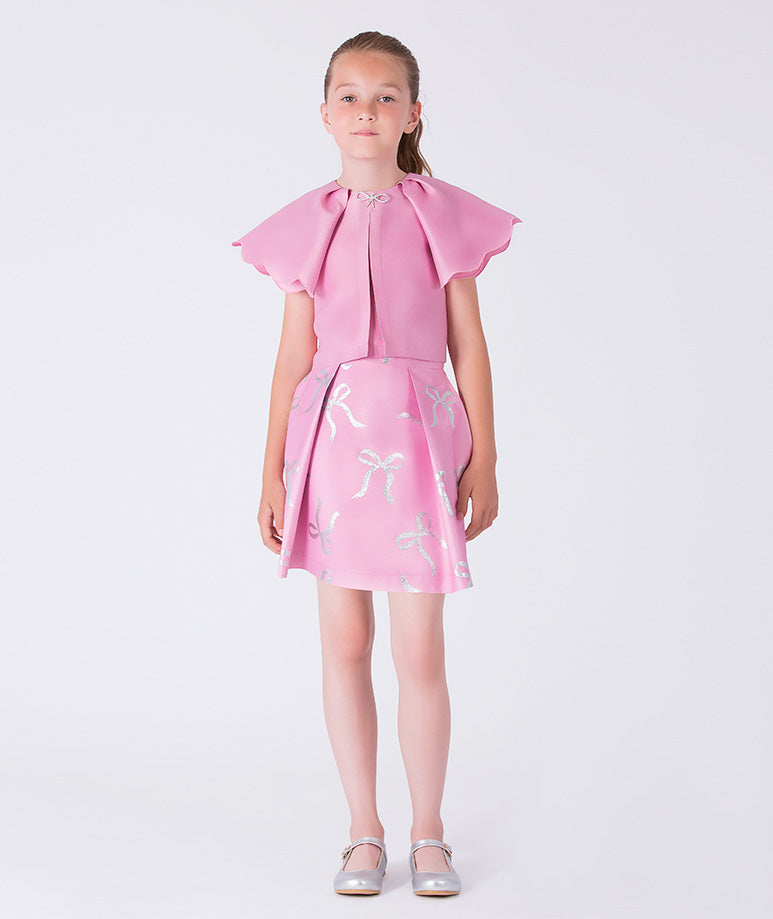 12 years old girl wearing a pink dress with bow details on a white background