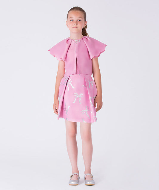12 years old girl wearing a pink dress with bow details on a white background