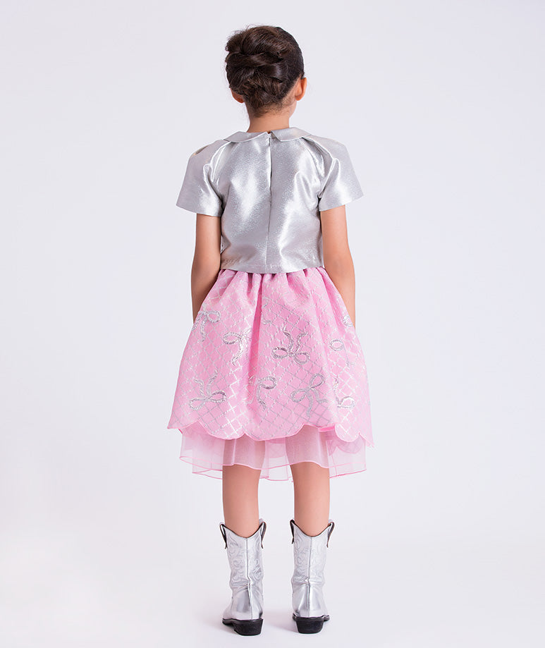 11 years old girl wearing a silver top and pink skirt with butterfly patterns on a white background