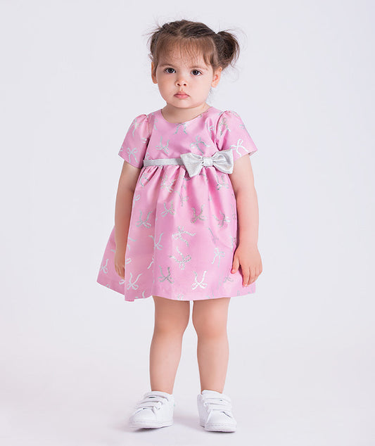 baby girl wearing a pink dress with butterfly patterns on a white background