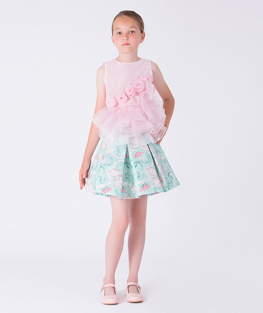 6 YEARS OLD girl wearing a pink top and floral skirt on a white background