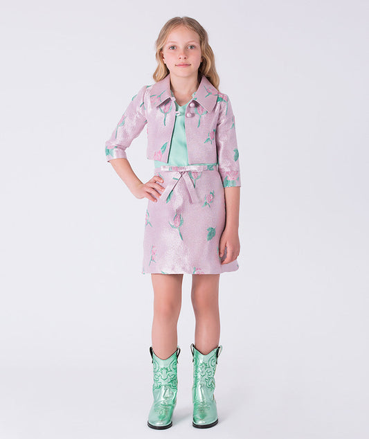Girl wearing a pink floral dress with a green belt and green boots on a white background