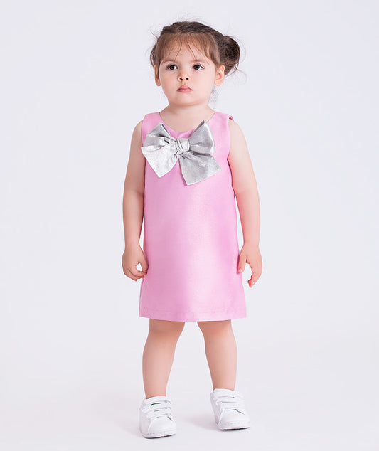 baby girl wearing a pink dress with a large silver bow on a white background