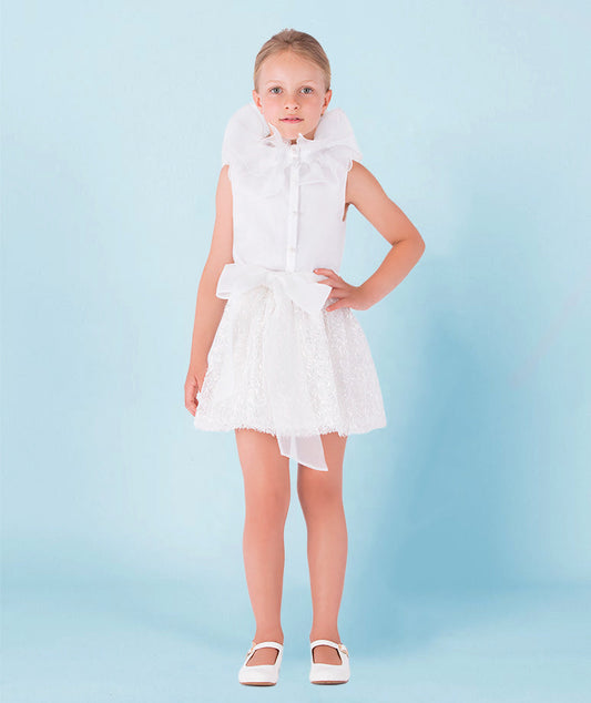 white blouse with organza ruffled neckline and shimmering skirt with an organza bow on the waist