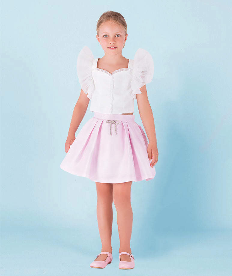 white ruffled blouse and baby pink skirt with a little sparkling bow on the waist 