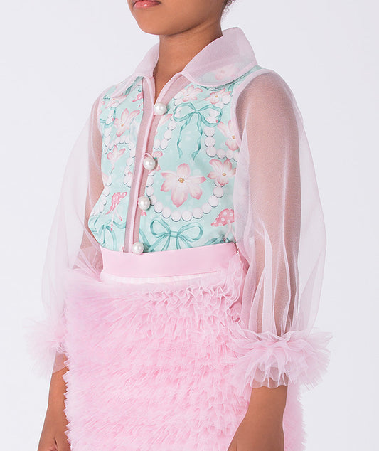 toddler wearing a floral top with a sheer pink jacket and pink skirt on a white background