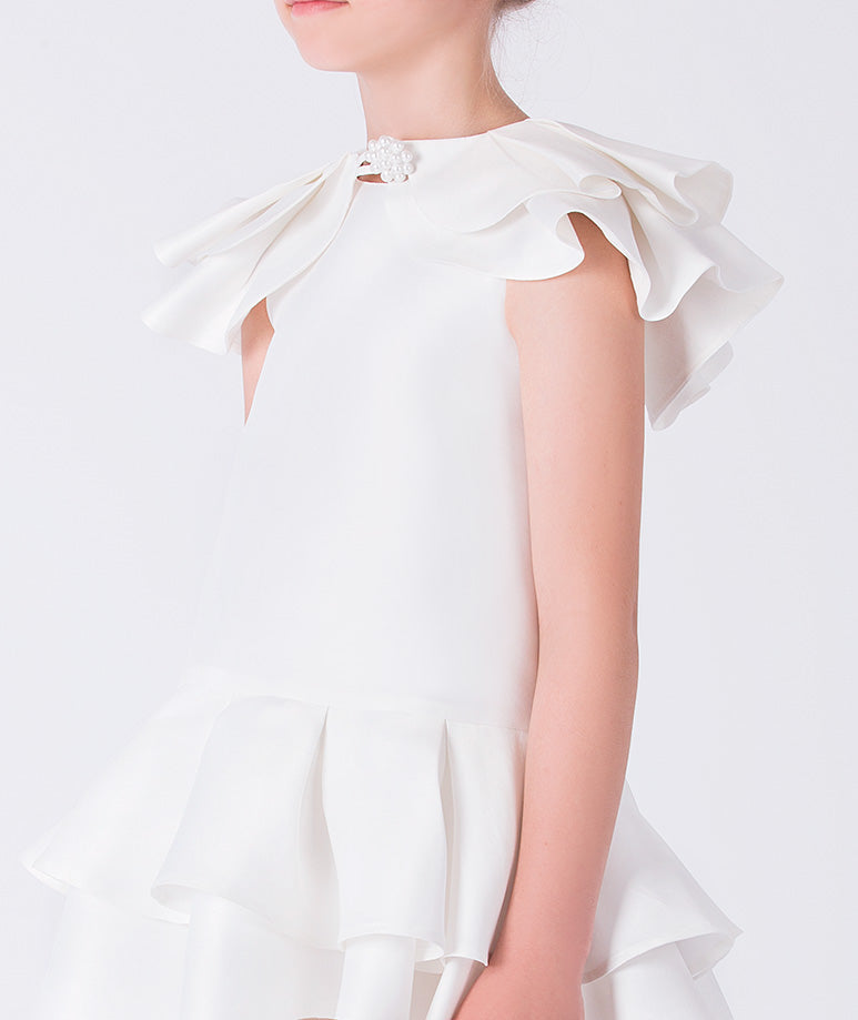 Close-up of layered ruffle sleeves and neckline detail on ivory girls occasion dress.
