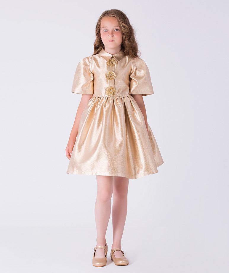 Front view of golden satin girls dress with floral brooch embellishments and structured A-line skirt from Golden Amara collection.