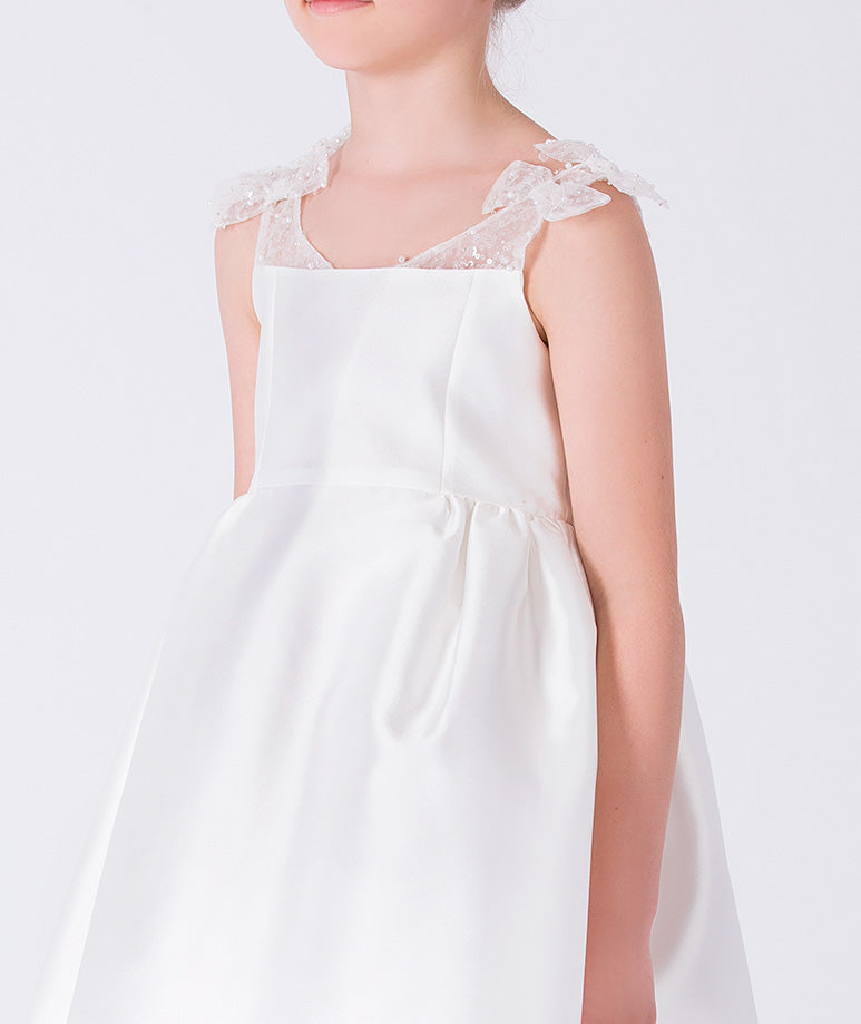 Close-up detail of beaded sheer straps on ivory elegant girls occasion dress.