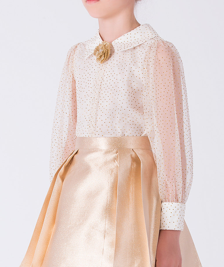 Close-up of gold girls outfit with sheer polka dot blouse, pointed collar and floral brooch detail