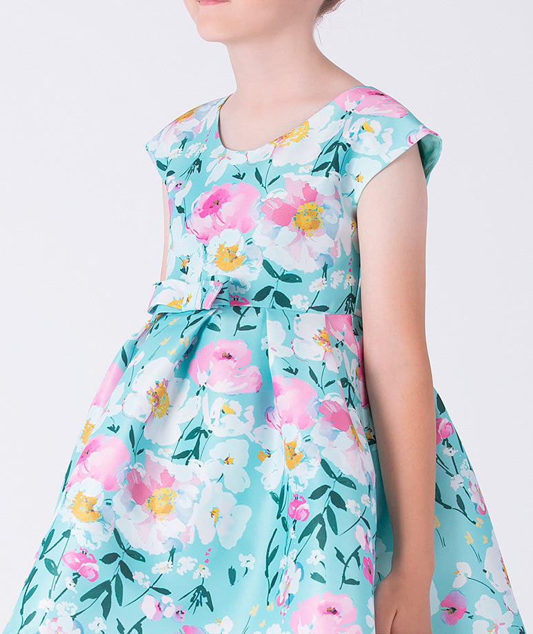Close-up of Kohana Petals Girls Dress featuring soft woven fabric, floral pattern, round neckline, and cap sleeve detail.