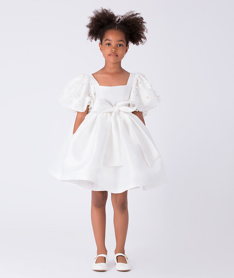 Front view of ivory girls dress with pearl beaded puff sleeves, square neckline and statement waist bow.