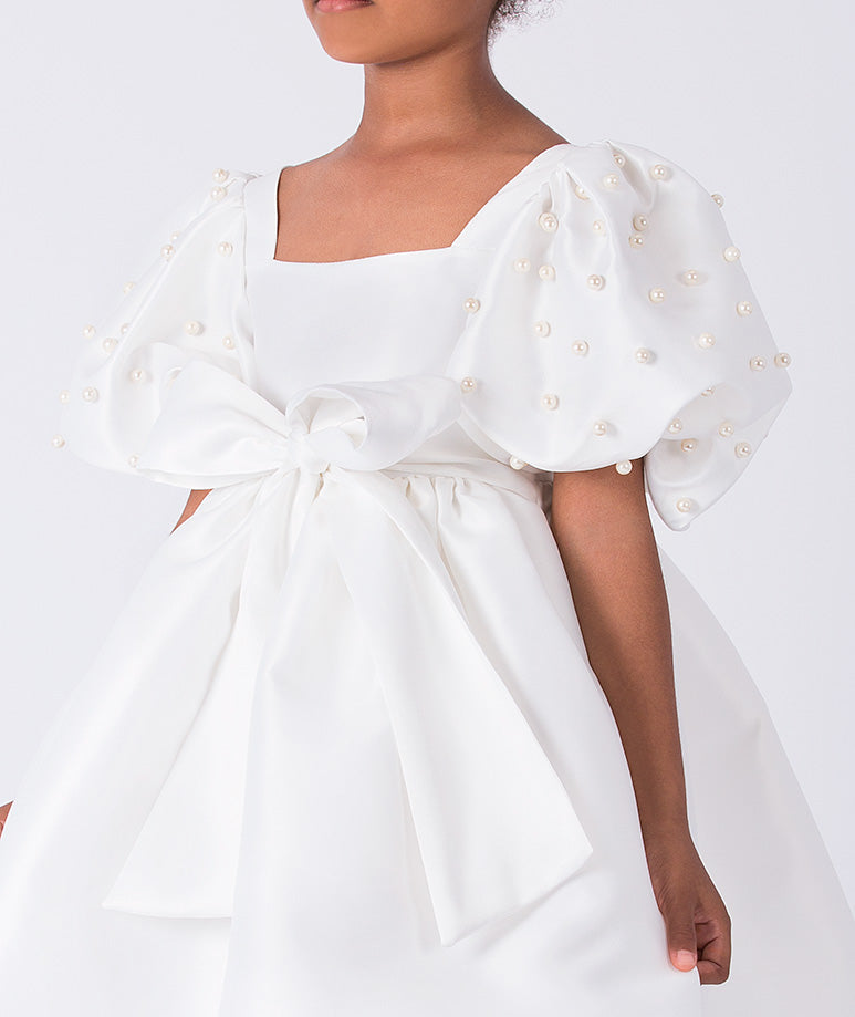 Close-up of pearl embellished puff sleeve on ivory girls occasion dress with structured bodice.