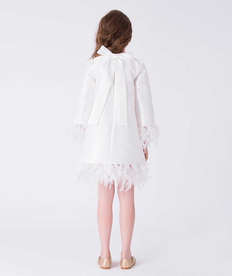 Back view of ivory A-line girls dress featuring bow detail and feather embellished hem.