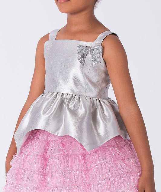 3 year old wearing a silver top with embellishments and a pink skirt on a white background