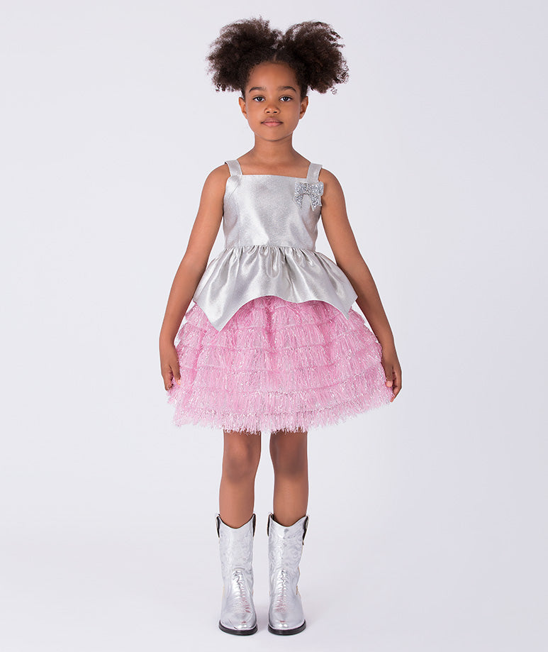 4 years old girl wearing a silver top and pink skirt with white boots on a white background