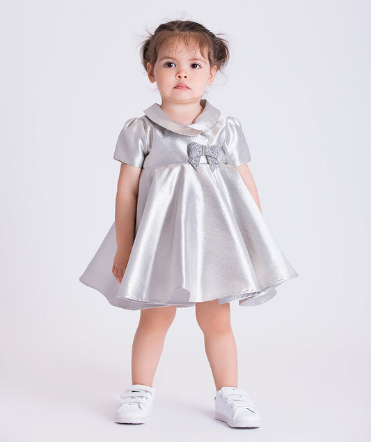 baby girl wearing a silver dress with a bow on a white background
