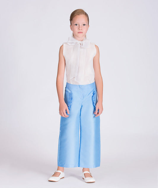 white blouse with a bow on the neck and blue pants 