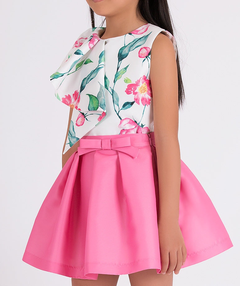 white floral blouse and pink skirt with a little bow on the waist